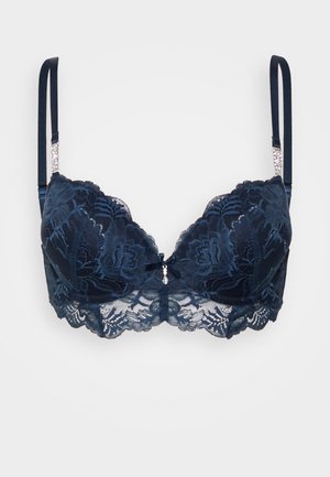 Soutien-gorge en dentelle bleu marine avec des bords festonnés, armatures, motifs floraux, bretelles réglables et un détail en gemme décoratif au centre.