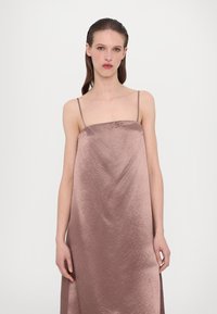 Satin glidkjole i myk mauve med tynne stropper, som har rett halslinje, voluminøs silhuett og subtilt teksturmønster.