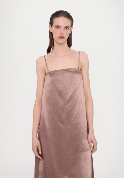 Σατέν φόρεμα slip σε απαλή μωβ απόχρωση με λεπτές τιράντες, διαθέτοντας ευθύ κόψιμο, όγκο στη σιλουέτα και διακριτό υφασμάτινο μοτίβο.