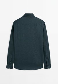 Dark green long-sleeve shirt with a collar, buttoned cuffs, and a textured finish. The back features a yoke and a slightly curved hem.