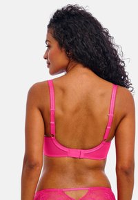 Soutien-gorge rose avec bretelles réglables et fermeture à crochets. Tissu lisse avec des détails en dentelle le long des bords. Vue de dos.