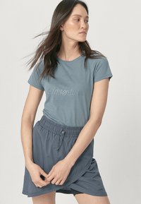 Lichtblauw T-shirt met "Adventure" in een subtiele opdruk, gecombineerd met een grijze rok met elastische tailleband en een trekkoord.