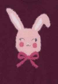 Bordeauxfarbener Pullover mit einem fuzzy, hellrosa Hasengesicht, langen Ohren, rosigen Wangen und einer dunkelrosa Schleife. Weicher Stoff mit verspieltem Design.