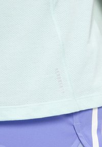 Tessuto azzurro chiaro testurizzato con piccole perforazioni sopra un tessuto viola chiaro caratterizzato da strisce verticali bianche.