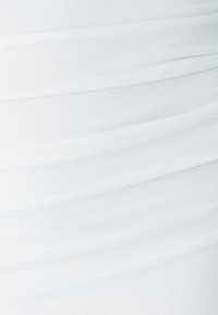 Gros plan d'un tissu blanc avec des plis horizontaux doux et une texture lisse.