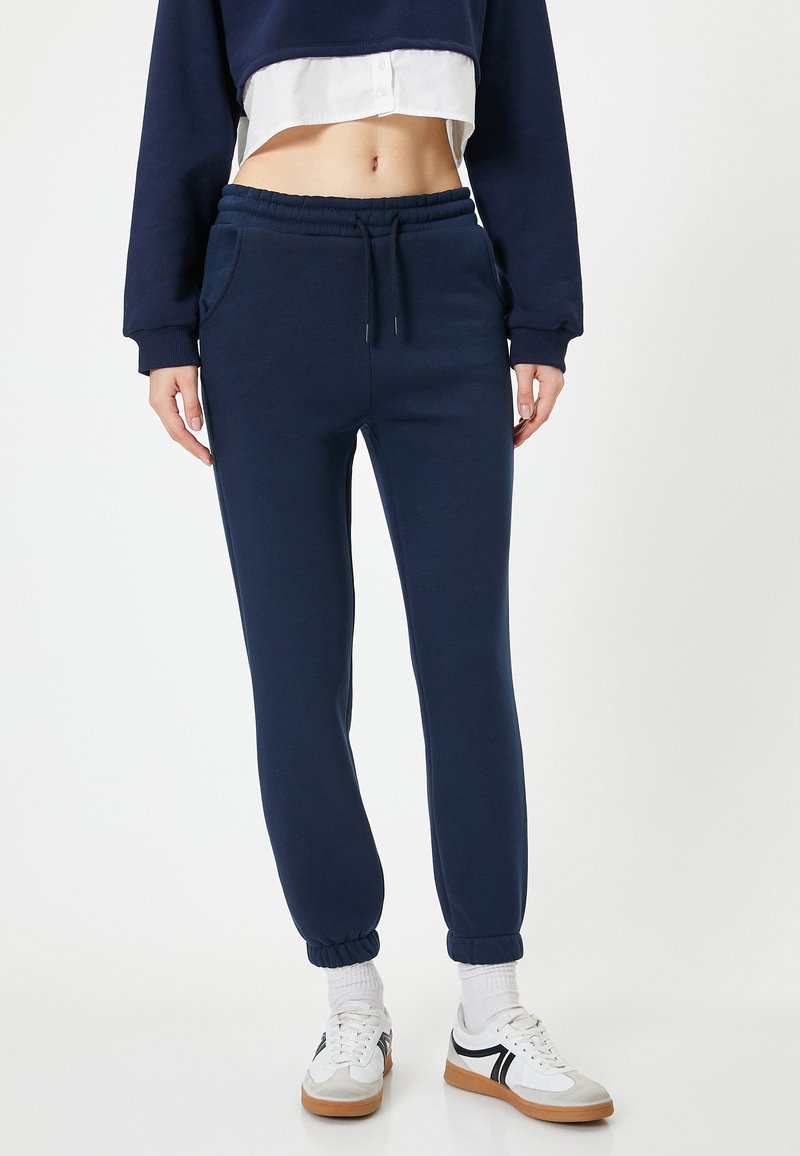 Marina blå joggers i mjukt material, med elastisk midja, sidofickor och ribbade muddar vid anklarna.