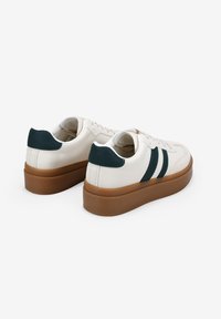 Zapatillas de cuero blancas con acentos verdes, suela de goma texturizada, punta redonda y dos rayas verde oscuro a los lados. Diseño bajo.