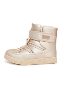 Stivali alti beige realizzati in materiale sintetico lucido. Suola spessa e texture con dettagli di lacci e cinturino in velcro alla caviglia.