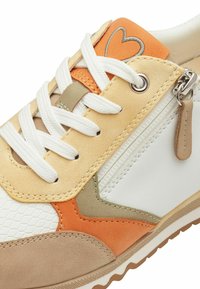 Scarpa sneaker beige e bianca con accenti arancioni e verdi. Presenta una superficie testurizzata, lacci bianchi e una cerniera laterale con un pull tab color beige.