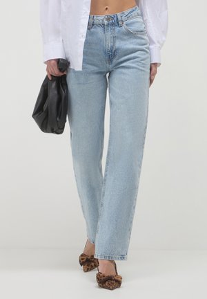 Helle blaue, hochgeschnittene Jeans mit geradem Bein, die dezente Verwaschungen und ein klassisches Fünf-Taschen-Design aufweisen, kombiniert mit einer schwarzen Tasche.