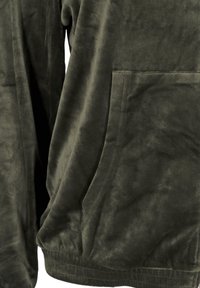 Tessuto in pile verde scuro con una texture morbida, caratterizzato da una tasca a marsupio e una vita elasticizzata. Design semplice e casual.