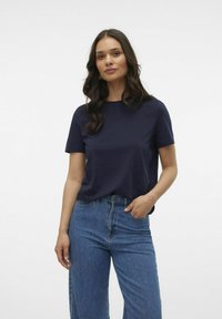 Mörkblå t-shirt med kort ärm i mjukt material, kombinerad med högmidjade blå jeans. Enkel, klassisk design med en avslappnad passform.