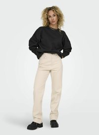 Svart crewneck sweatshirt, beige högmidjade raka byxor och svarta låga skor. Egenskaper inkluderar lös passform och texturerad tyg.