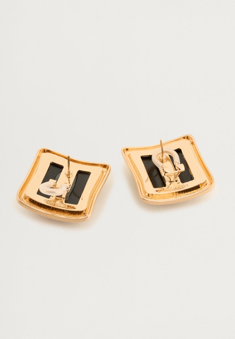 Gold-tone earrings with a square design, featuring a black base and white accents. Textured surface with a glossy finish and distinct hardware.