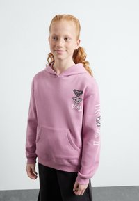 Haut à capuche rose avec une poche kangourou, avec un imprimé graphique sur la poitrine et la manche. Tissu doux et coupe décontractée.