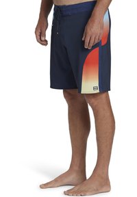 Bañador de hombre en color navy, con un diseño degradado en naranja y amarillo en el lateral, fabricado en tela ligera con cintura ajustable mediante cordón.