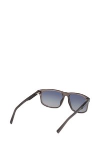 Occhiali da sole con forma rettangolare, montatura grigia trasparente, lenti blu sfumate e aste marroni texturate. Presentano dettagli metallici sulle cerniere.