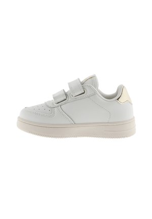 Baskets en cuir blanc avec deux bandes Velcro réglables, bout rond, perforations minimales, semelle beige et un accent métallique doré subtil au niveau du talon.