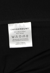 Black fabric with a care label reading "SWEDEMOUNT," detailing 60% Merino wool, 40% Tencel, and wash instructions in multiple languages.