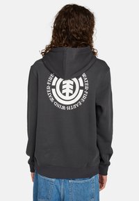 Sudadera con capucha de color gris oscuro, con un gran gráfico circular blanco en la parte posterior. Cuenta con capucha con cordón y puños y dobladillo acanalados. Fabricada con tela suave.