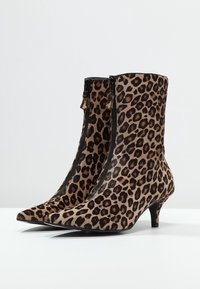 Stivaletti alla caviglia con stampa leopardata, punte appuntite, tacco kitten basso, chiusura con cerniera laterale e texture in tessuto morbido.