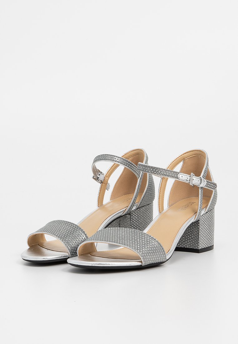 Sandales argentées à talons, avec texture en maille, design à bout ouvert, brides de cheville et talon bloc. Présente un accent métallique lisse sur la semelle.