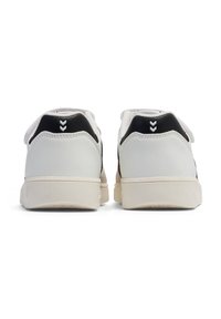 Sneakers in pelle con una parte superiore bianca, accenti neri sul tallone e suole beige texturizzate. Presentano un logo bianco in contrasto sul retro.