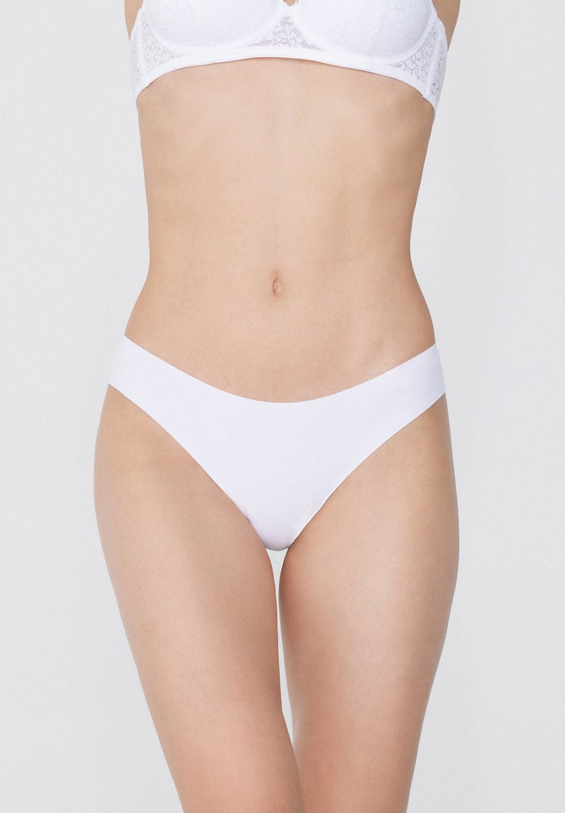 Bílé bavlněné bikiny s hladkým povrchem a nízkým pasem. Design má bezešvý pas pro pohodlí.