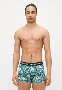 Herren-Boxershorts mit einem tropischen Blätterdruck in grün und türkis sowie einem schwarzen Bund mit der Aufschrift "JACK & JONES". Aus Baumwollmaterial, enganliegendes Design.