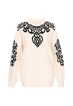 Bež džemper s crnim izvezenim ukrasnim uzorcima na prsima i rukavima. Ima okrugli izrez i rebraste manžete.