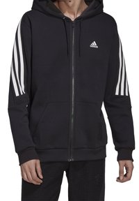 Felpa nera con zip e tasca frontale, logo Adidas bianco sul petto e design a tre strisce bianche su entrambe le maniche.