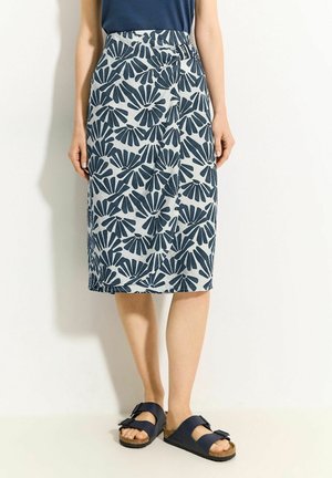 Rok van middellange lengte met een blauw bloemenpatroon op een lichte achtergrond, gemaakt van zacht stof met een lichte glans. Draagbaar met donkere sandalen.