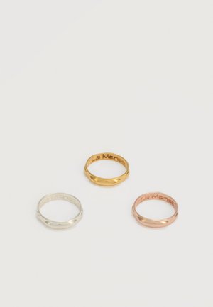 Tri hladké kovové krúžky v striebornej, zlatej a ružovo zlatej farbe, každý s vyrezávaným nápisom "La Manso" vo vnútri.