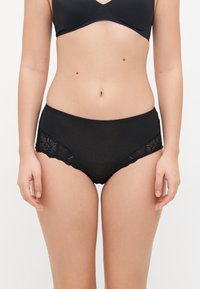 Black cotton brief with lace accents, featuring a scalloped edge and floral pattern on the sides. Soft texture, mid-rise design.