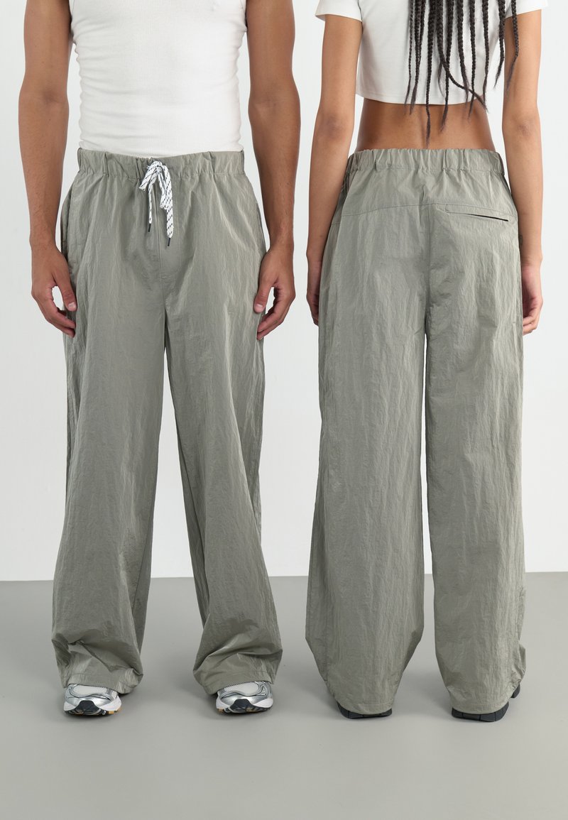 Pantalons larges gris clair en tissu texturé. Équipés d'une taille élastique avec cordon de serrage. Comprend un détail de poche arrière.