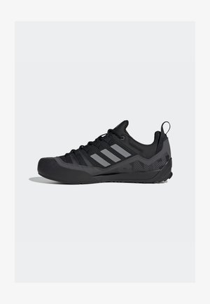 Juoksujalkineet musta verkkomateriaali, kuminen varvaspäällinen, harmaat Adidas-raidat ja teksturoitu pohja parannetulle pidolle.