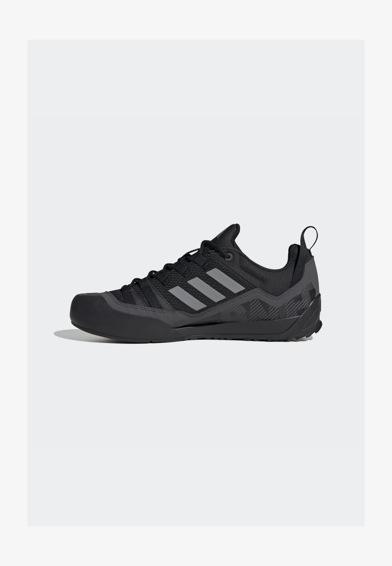Black athletic shoes featuring a mesh upper, rubber toe cap, grey Adidas stripes, and textured sole for enhanced grip.