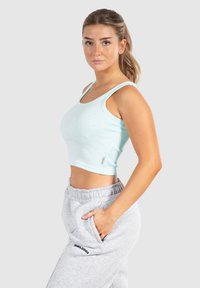 Ljusblå ribbad crop top med tunna axelremmar. Kombinerad med grå sweatpants med sidofickor och en svart logodetalj.