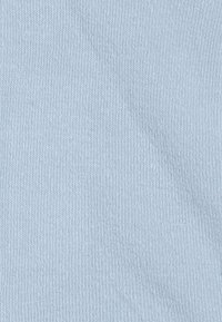 Hellblaues gestricktes Material mit feiner Rippenstruktur. Der Stoff wirkt weich und glatt und zeigt subtile Farbnuancen.