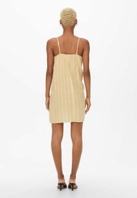 Geel gestreepte sundress met spaghettibandjes, ontspannen pasvorm en lichtgewicht stof, tot halverwege de dij, gladde textuur. Minimalistisch ontwerp.