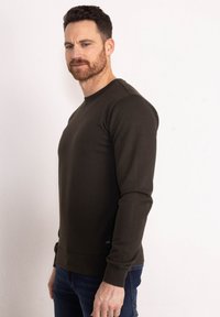 Dark green long-sleeve sweatshirt made of soft fabric, featuring a round neckline and ribbed cuffs. Slim fit with minimal branding detail.