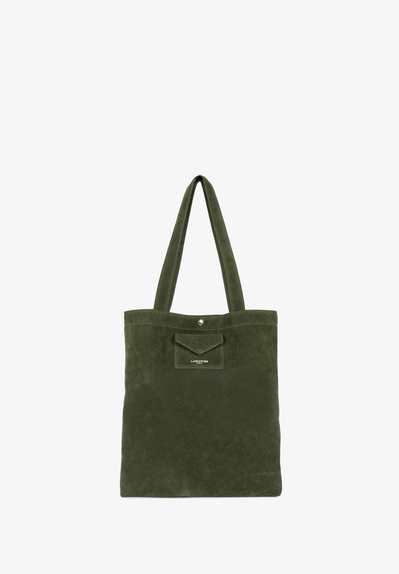 Groene suede tote bag met twee lange handvatten, voorkantvak met drukknoopsluiting en reliëflogo. Plat ontwerp met een zachte textuur.