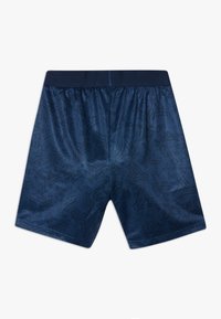 Marinblå atletiska shorts med ett abstrakt mörkt mönster, elastisk midja och slät textur. Designade för komfort och rörelsefrihet.