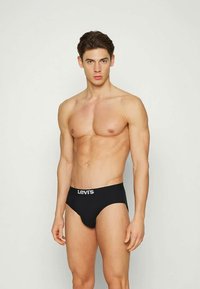 Boxeri negri Levi's cu un elastic cu logo, purtați de un model fără cămașă, evidențiind textura netedă și potrivirea materialului.