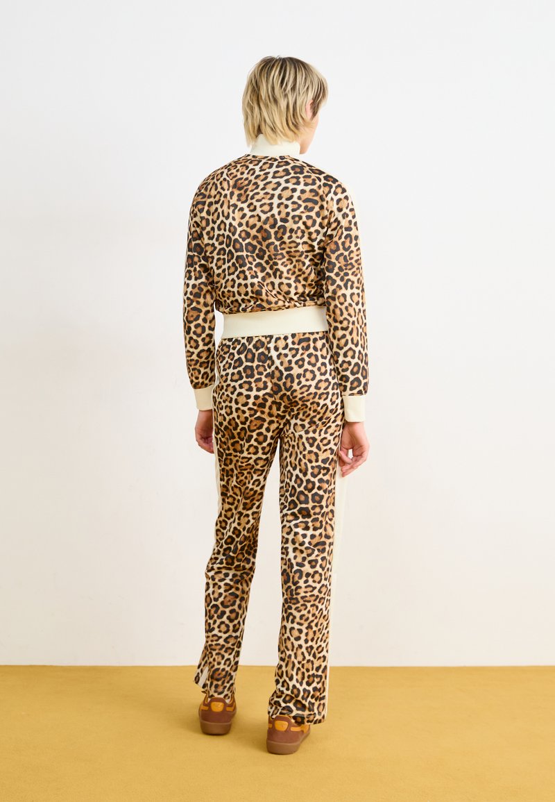 Ensemble de survêtement à imprimé léopard en tissu extensible, avec un col et des poignets côtelés, au design ajusté et des rayures sur les côtés du pantalon.