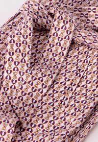 Bavlněná tkanina s květinovým vzorem v purpurové, oranžové a bílé barvě. Měkká textura, s vrstvami a skladbami, vytvářející vizuální hloubku.