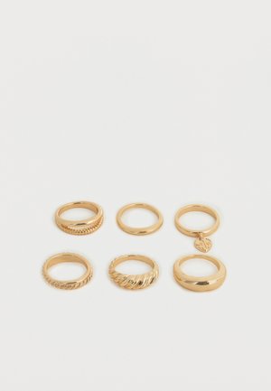 Seks guldfarvede ringe arrangeret i to rækker på en hvid baggrund, med glatte, snoede og charmerende designs.