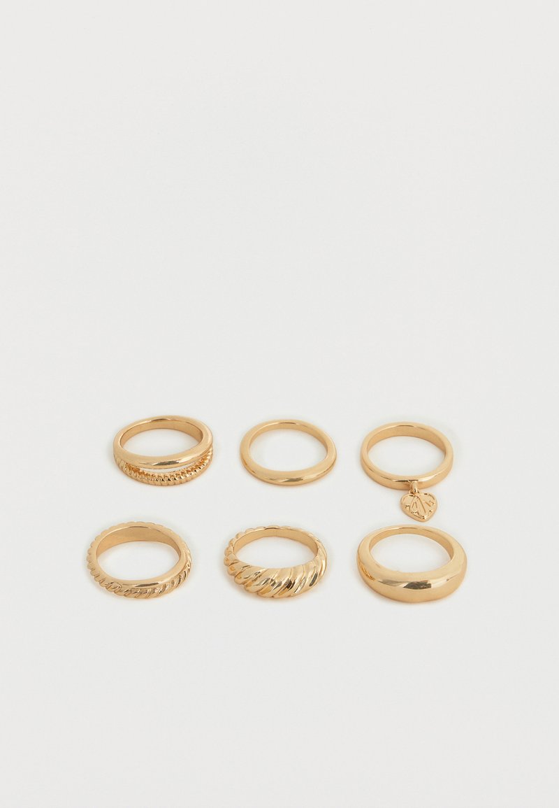 Έξι δαχτυλίδια σε χρυσό τόνο, τοποθετημένα σε δύο σειρές πάνω σε λευκό φόντο, με λείες, στριφογυριστές και με γοητευτικά σχέδια.