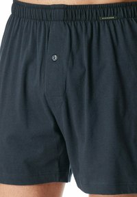 Boxer in cotone blu navy con vita elastica e chiusura frontale a bottone. Presenta un piccolo logo sulla vita.