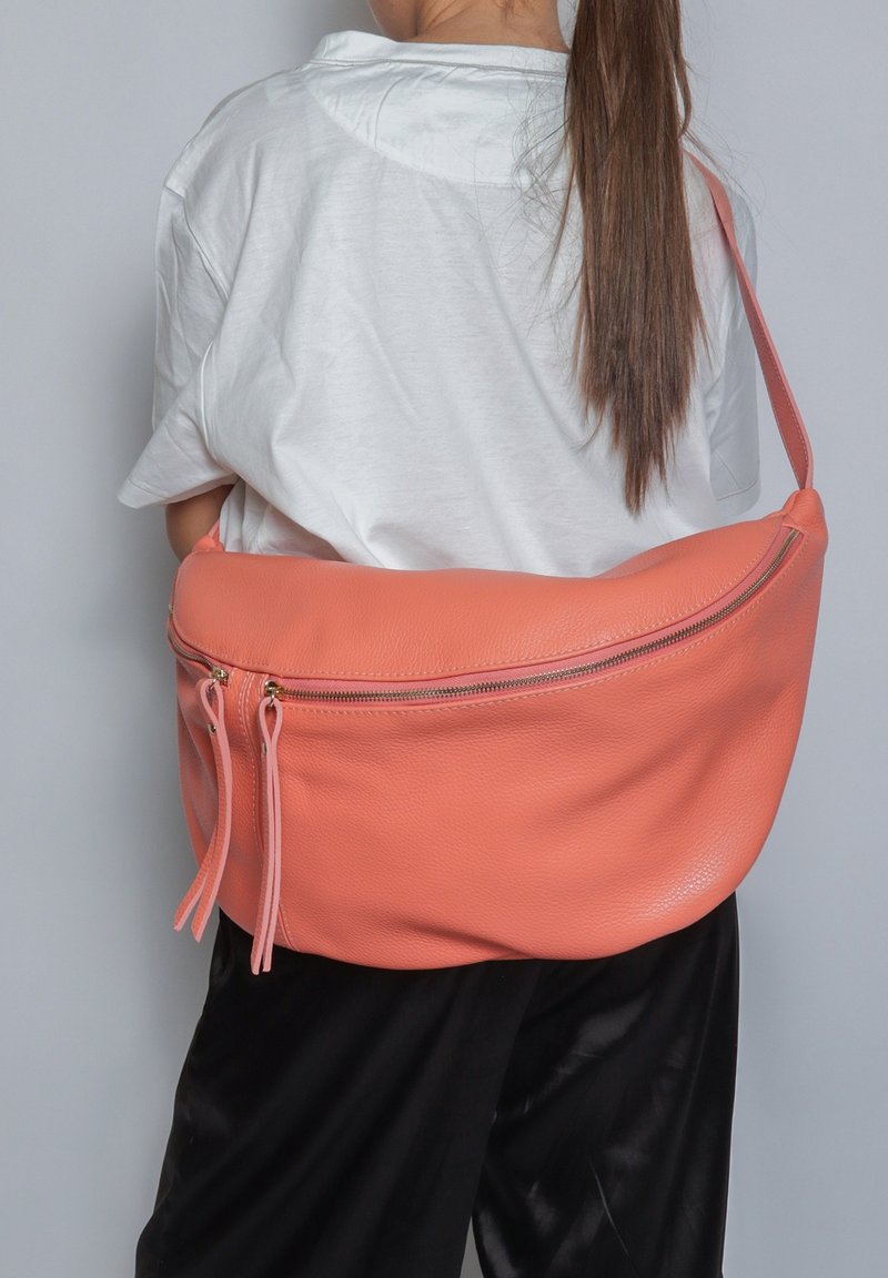 Grande borsa a spalla in pelle corallo con una texture liscia, dotata di una cerniera superiore e due tirazip decorativi. Il design è arrotondato e morbido.